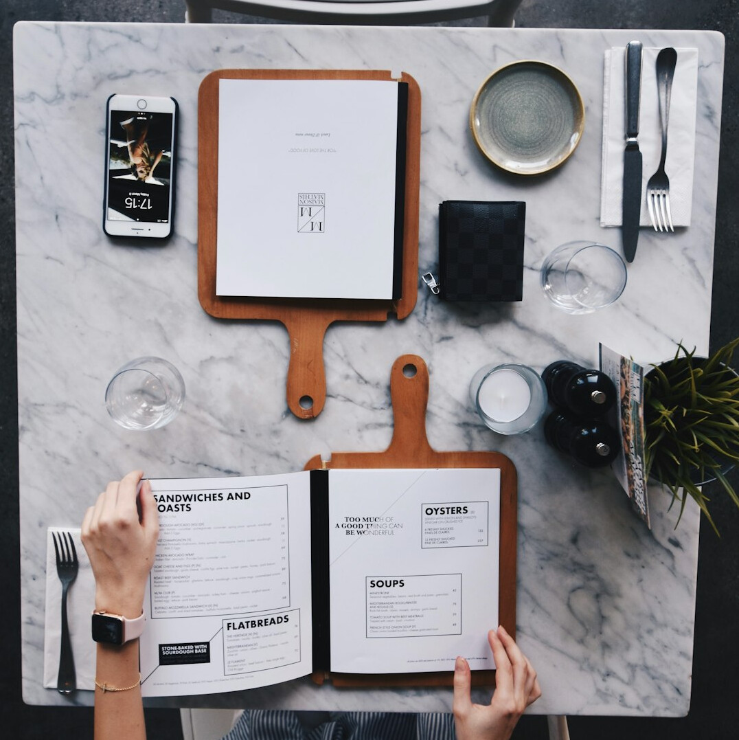 Overhead view of hands writing research notes beside open notebooks and documents