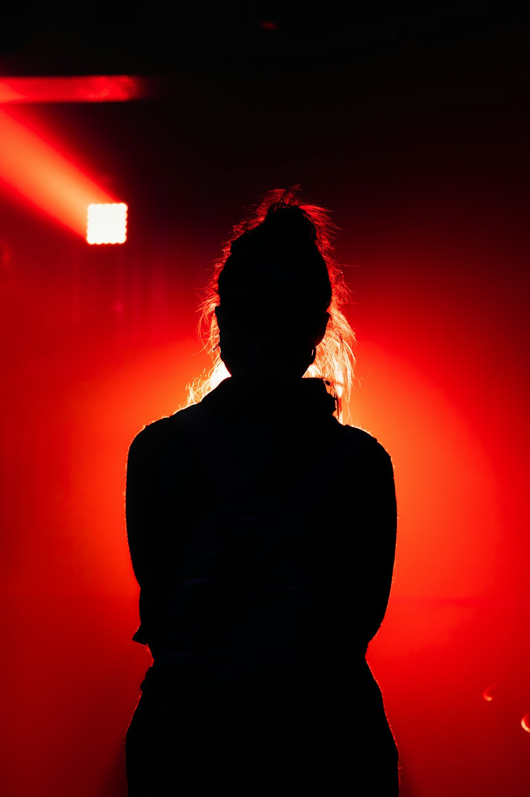 Silhouette of an anonymous person seated alone in a dark theater facing a lit stage